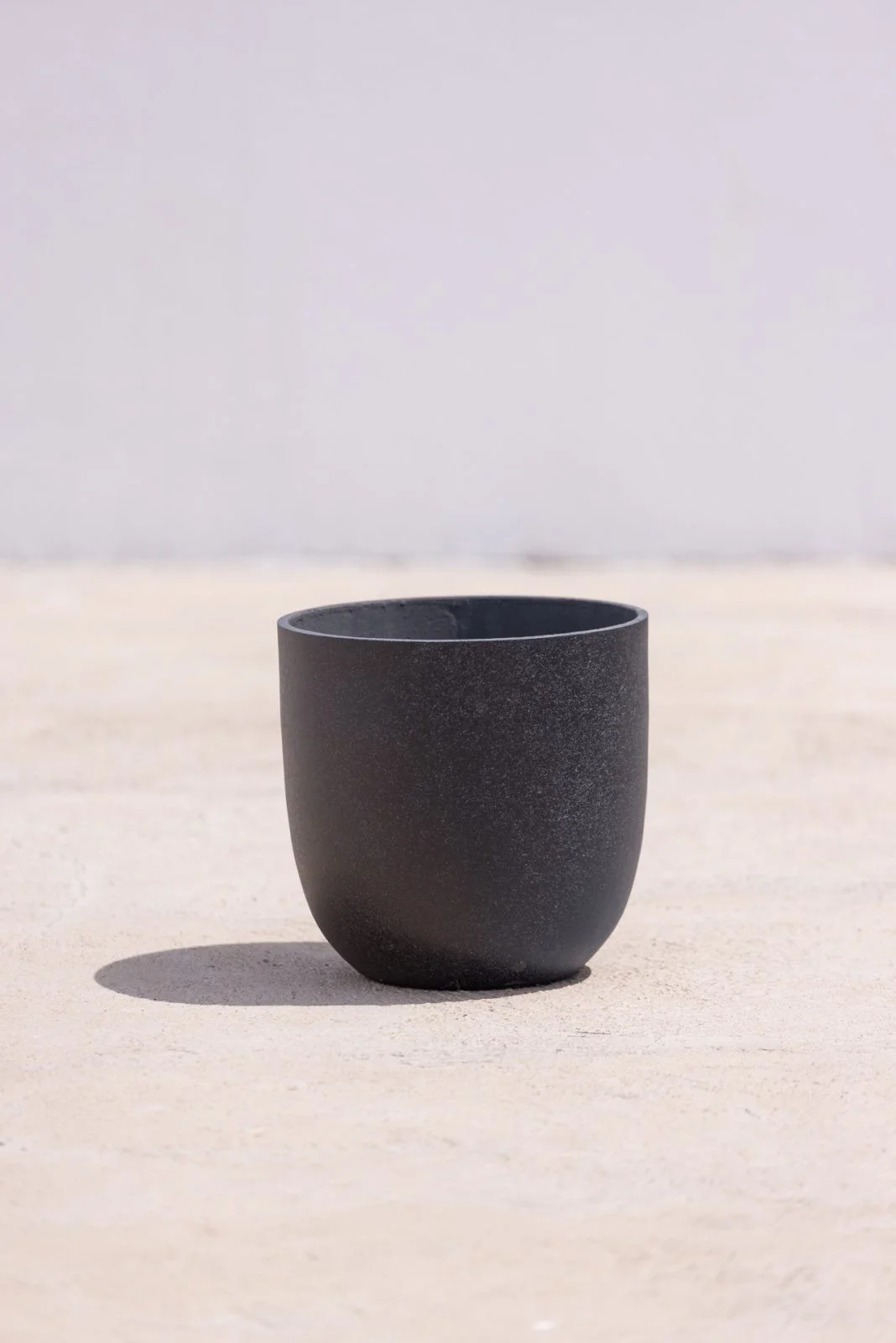 Modern black flower pots on a sunny South African stoep; charcoal black flower pots with colourful petunias; minimalist indoor black flower pots.